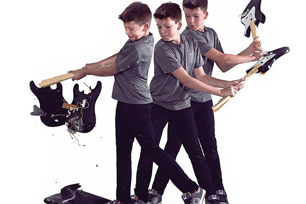 A boy smashes an electric guitar with gusto