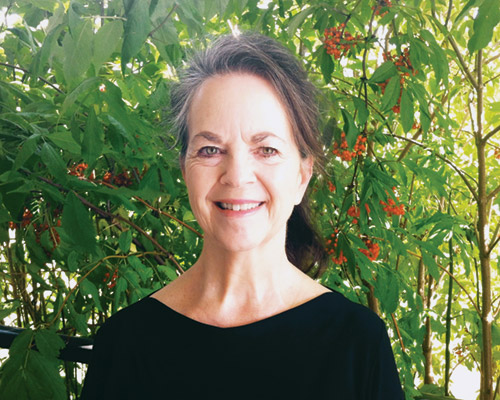 Donna Atkinson Smith posing in front of foliage.