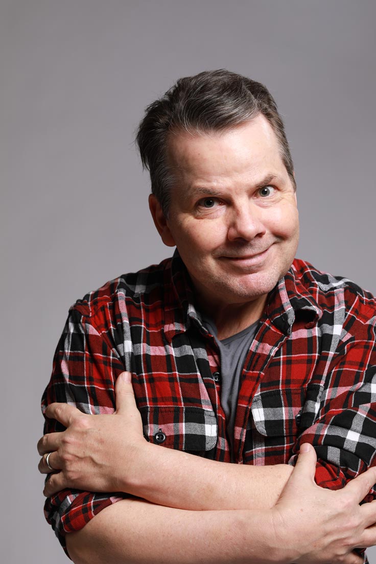Photo of Bruce McCulloch smiling and hugging himself.