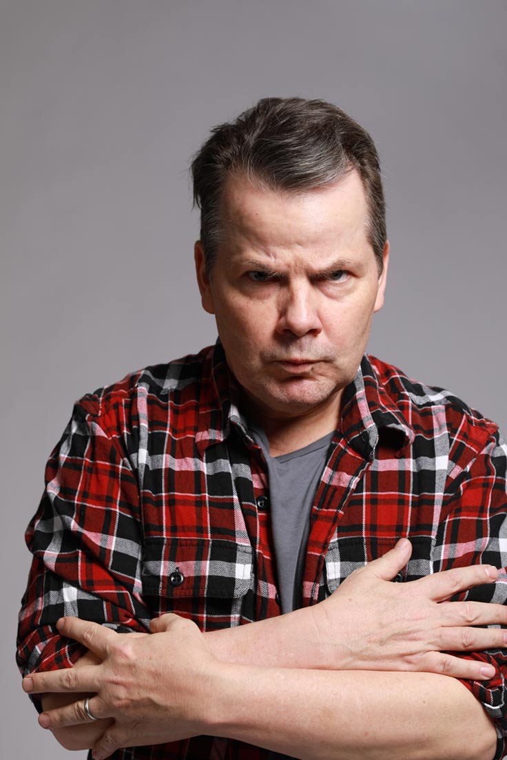 Photo of Bruce McCulloch frowning and hugging himself.