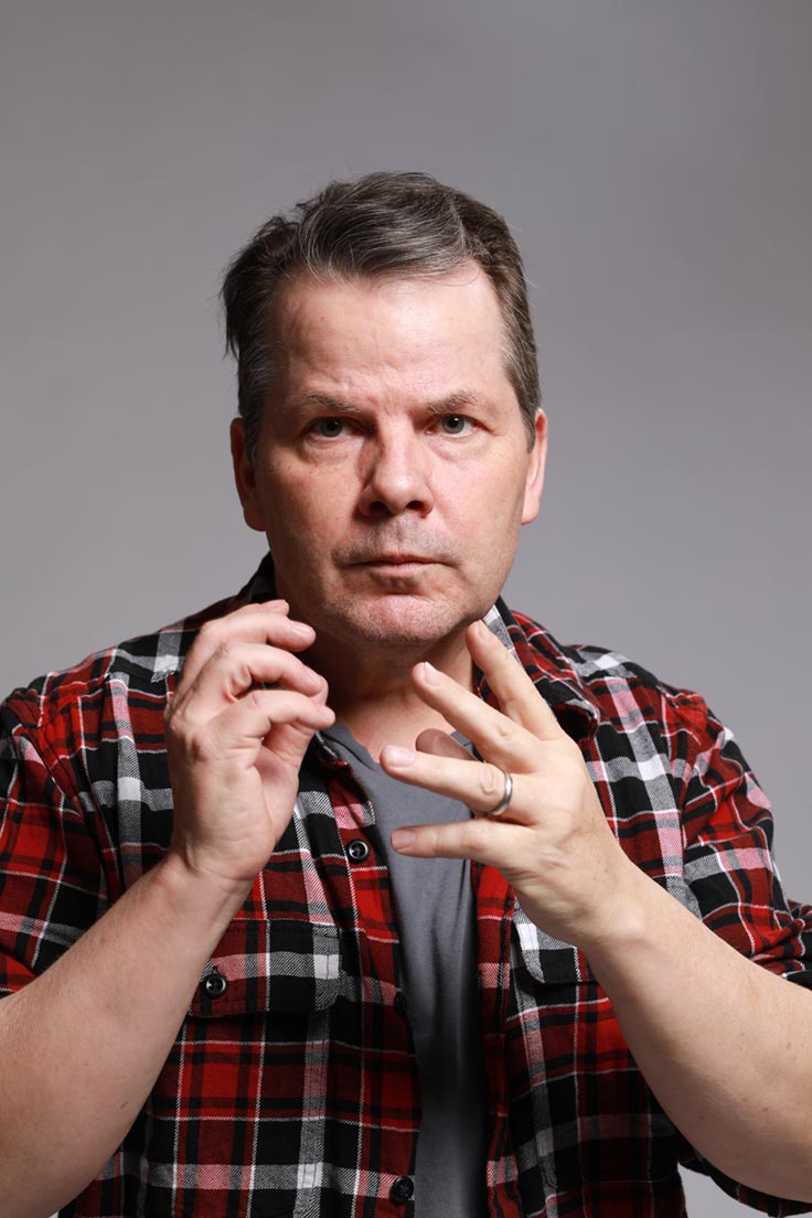 Photo of Bruce McCulloch with his lips pursed and his hands in front of him in an odd, nonspecific gesture.