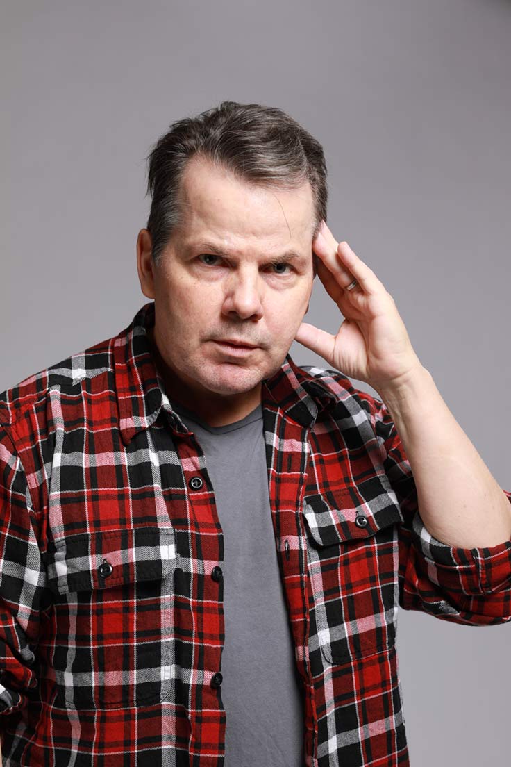Photo of Bruce McCulloch with his fingers of his left hand on his temple.