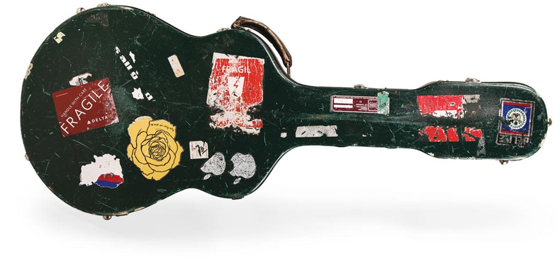 A well-worn guitar case covered in stickers