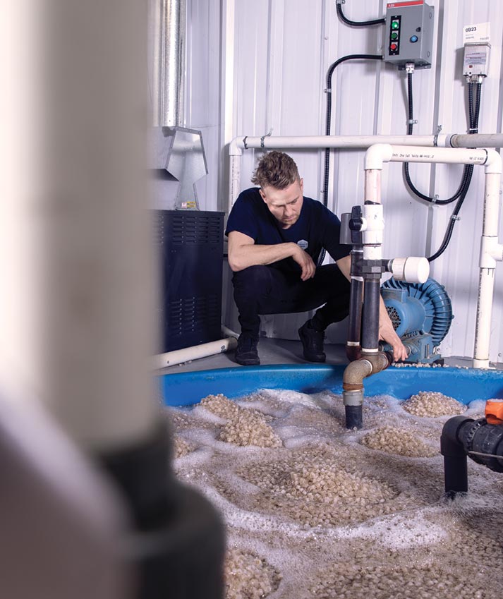 Paul Shumlich crouches over a vat of plant fertilizer