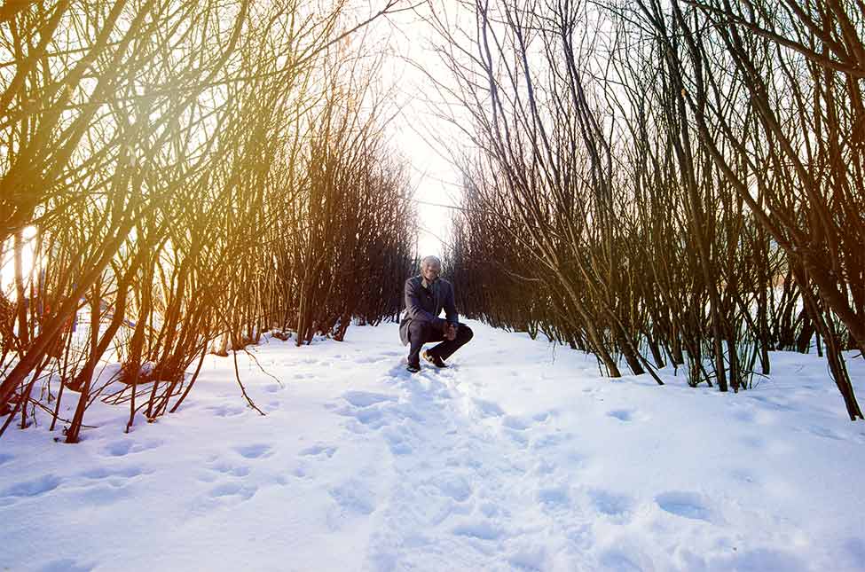 Nana Asante framed by a row of branches in a Calgary park