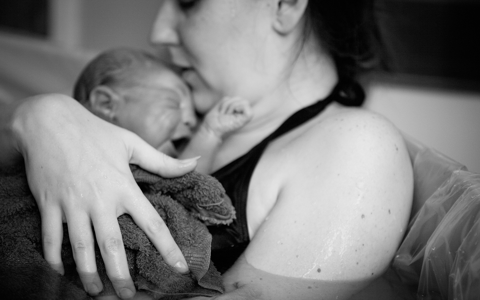 A new mother clutches her newborn child after a water birth.