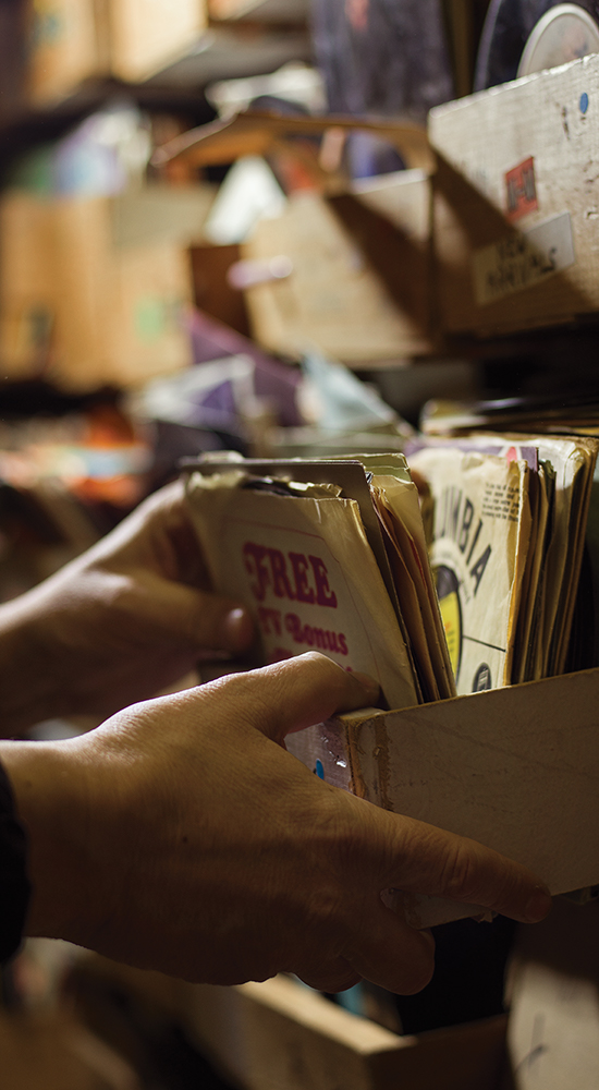 Hands sort through a drawer of records