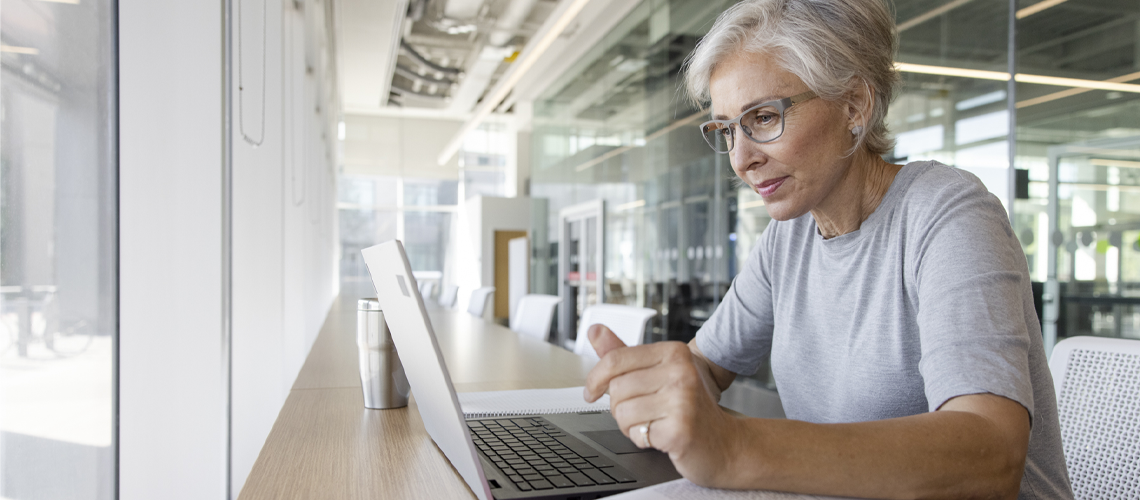 A senior woman engaged with a laptop, displaying concentration and interest.