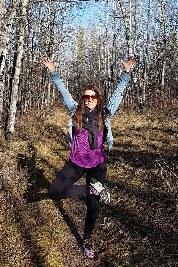 Julia Wenzel, posing triumphantly in a forest.