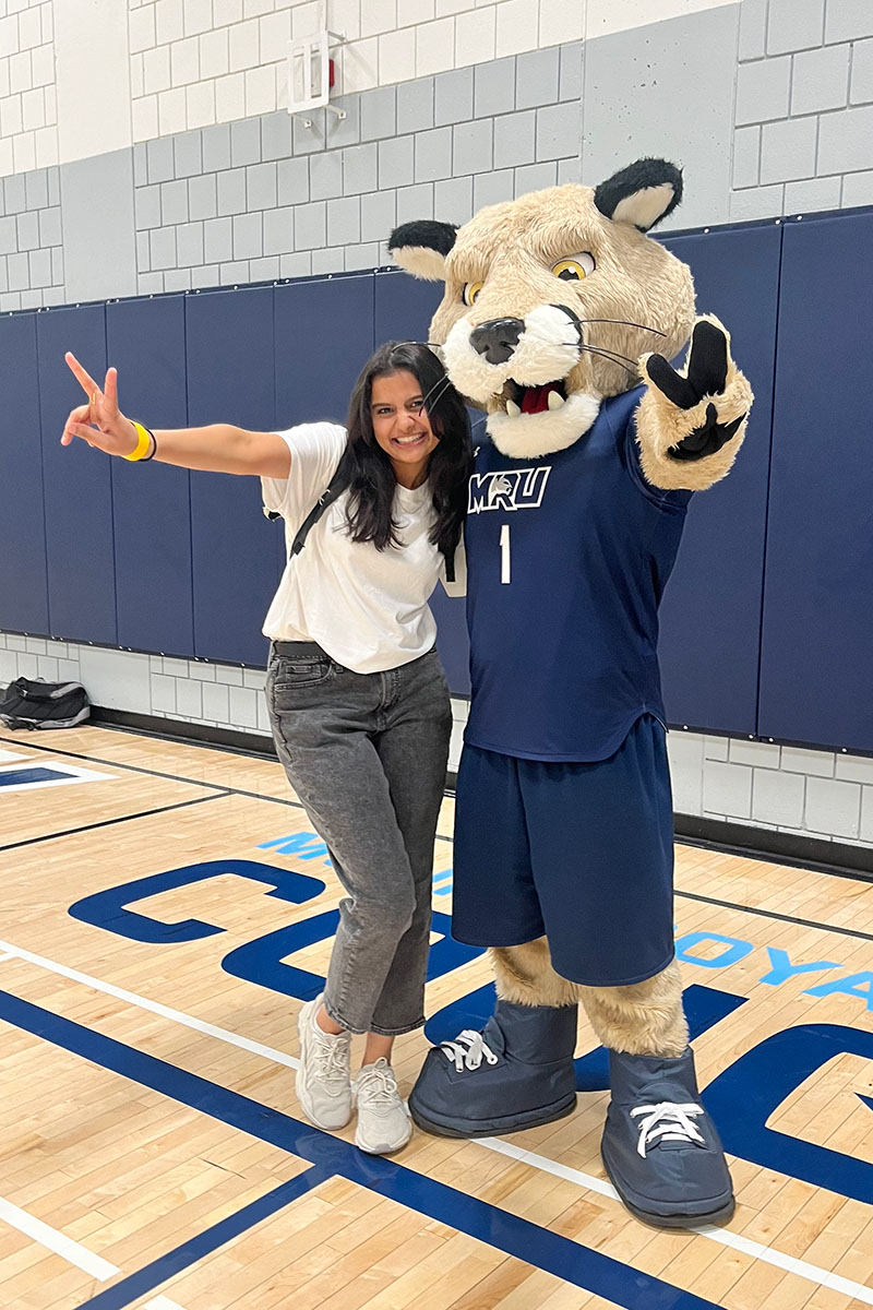 Raini Mahida posing with Mount Royal University Cougars' mascot, Calvin