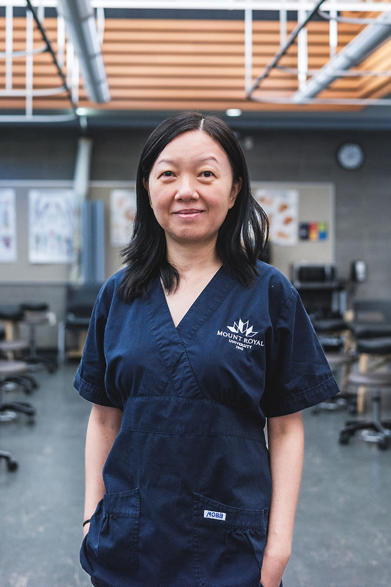 Nicole Dai wearing MRU scrubs in an MRU massage therapy classroom.