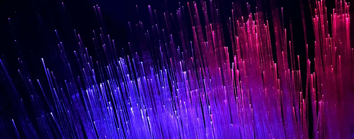 Fiber-optic cables filled with purple and pink light on a dark background.