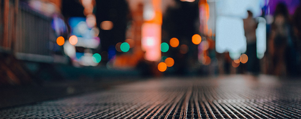 Blurred photo of Times Square in New York taken from near the ground looking up.