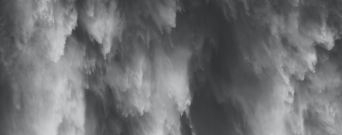 Black and white photo of the foamy spray of a waterfall.