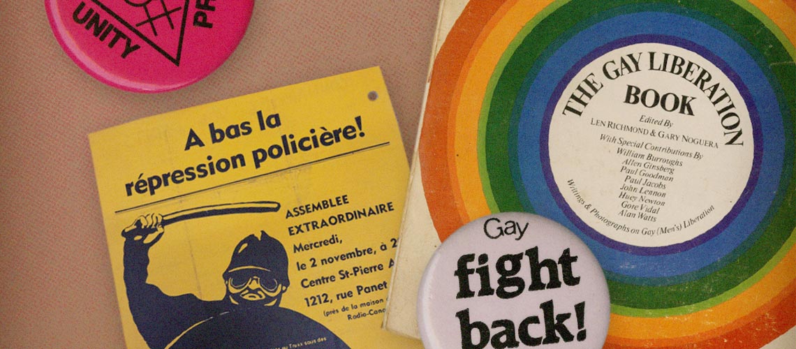 Colourful buttons and posters featuring historic LGBTQ+ slogans.