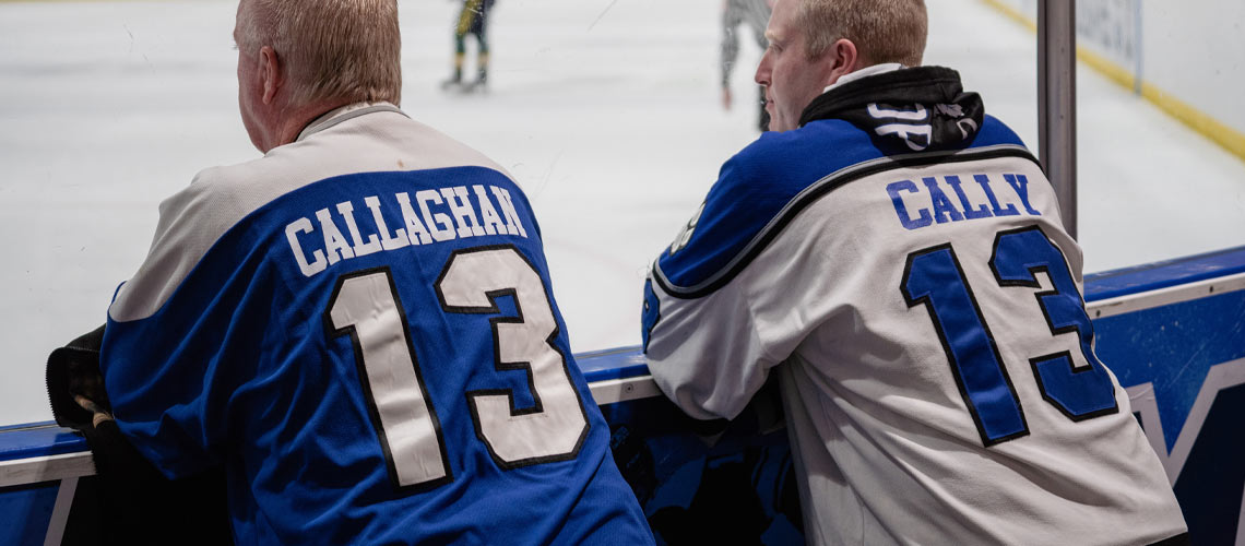Two men in hockey jerseys watching the game.