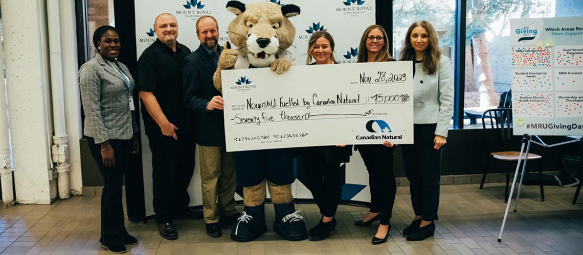 A team of people standing in front of a big check.