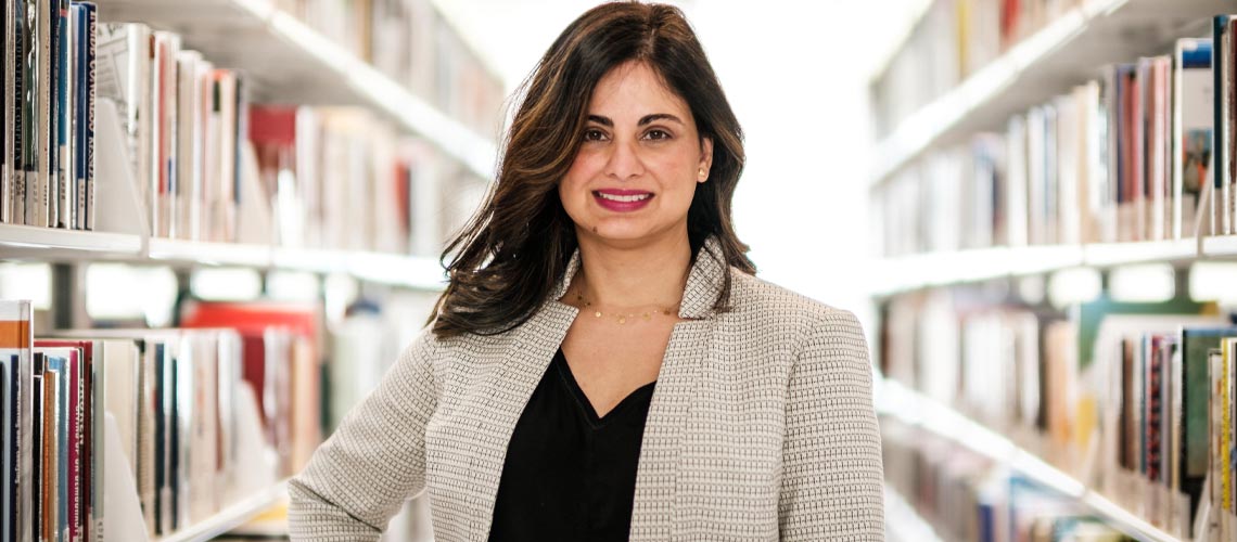 Dr. Aliyah Dosani, PhD, standing in the Riddell Library and Learning Centre.