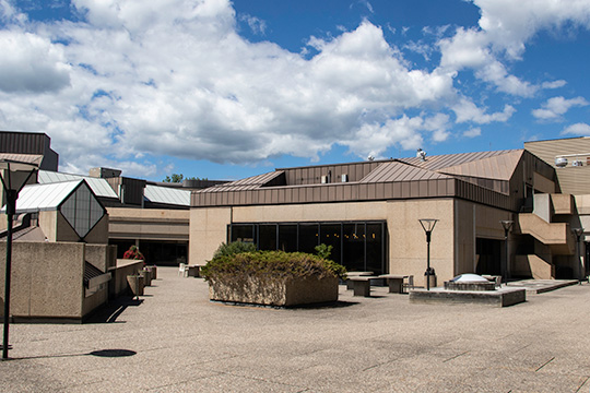 A concrete patio outside a concrete, brutalist style building.