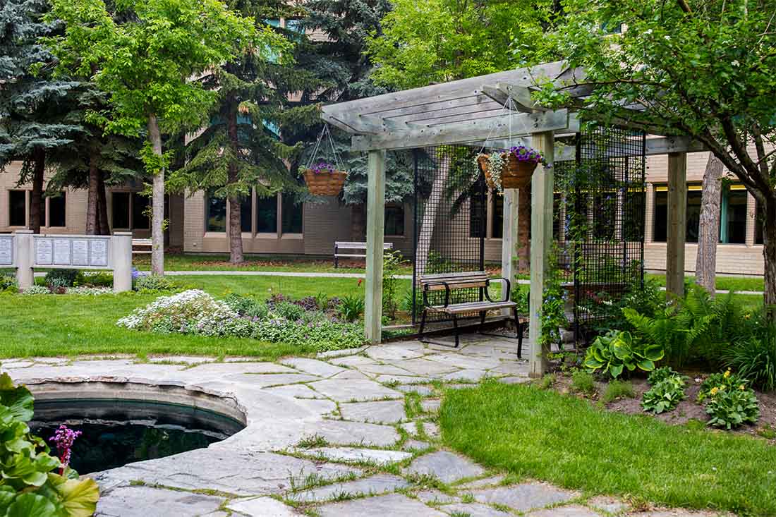 Photo of a garden with a stone lined pond and gazebo.