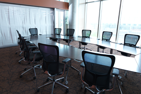 An unusually shaped conference table surrounded by chairs in the center of a modern looking room.