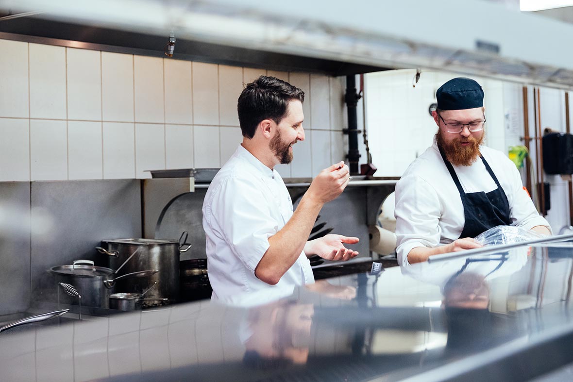 Hotel Arts Group executive chef Quinn Staple and fellow chef chatting in the Yellow Door Bistro kitchen